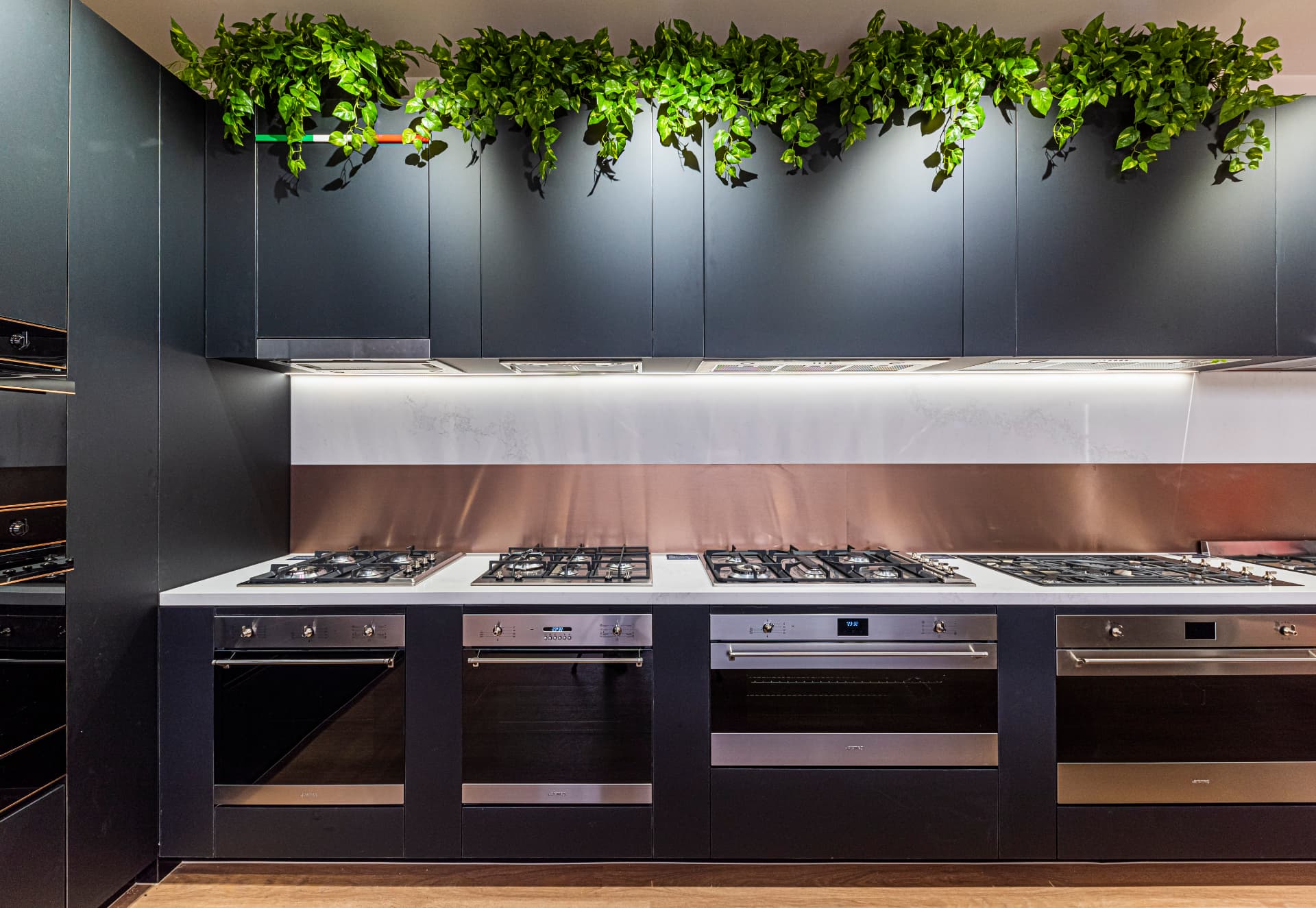 Harvey Norman kitchen display with detailed cabinetry and planting